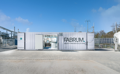 White Fabrum liquid hydrogen solution container with open doors at an industrial site.